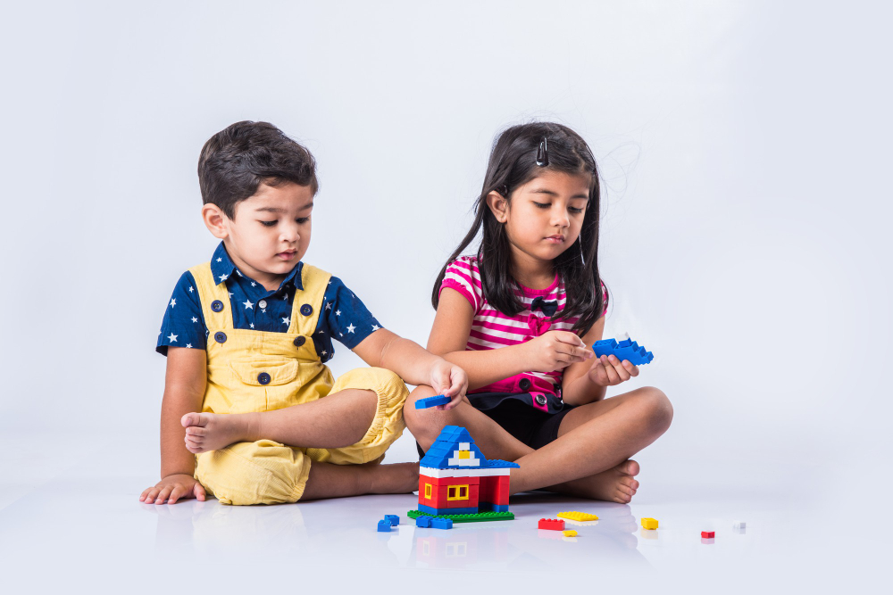 cute-little-indian-asian-kids-playing-with-toys-blocks-having-fun-while-sitting-table-isolated-white-background